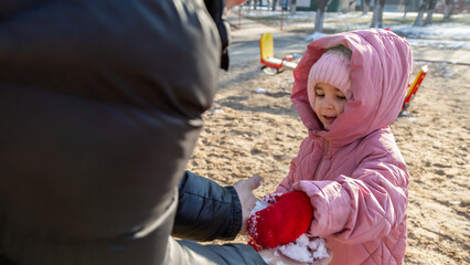 Grandfather playing with his granddaughter on the playground in the park in winter