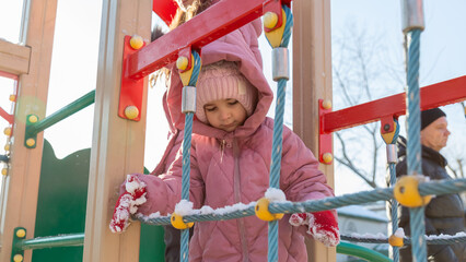 Girl playing on the playground on a cold winter day
