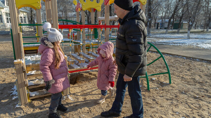 Grandfather with grandchildren playing on the playground on a cold winter day