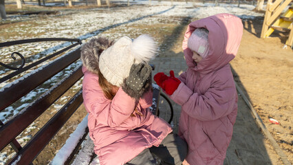 Two little children, quarreling and ready to beat each other crying during their walking in winter.