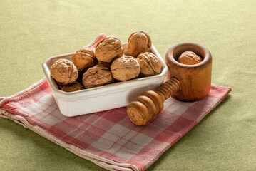 Heap of dry walnuts in a cup, with a screw-type nutcracker