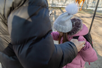 Grandfather walks with his granddaughter after school in the park in winter