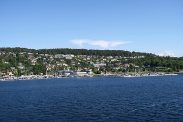 Frogn Drøbak, Akershus, Noway - 07 12 2024: Vom Sonnendeck der Fähre von Oslo nach Kopenhagen ist die Silhouette der Gemeinde Frogn Drøbak am Oslofjord zu sehen. Es ist ein sonniger Sommertag.