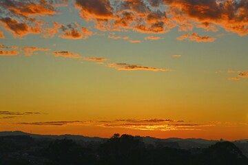  Above the city, beautiful clouds in vibrant colors. Dawn with reddish clouds in the sky. Sun rising over the horizon, yellow reflections in the sky.