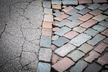 Fototapeta premium Close-Up of Cracked Asphalt and Cobblestone Pavement in Urban Area