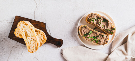 Liver pate on ciabatta on a plate on the table top view web banner