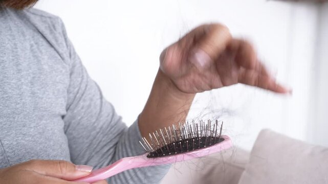 woman&rsquo;s hand holding a hairbrush full of fallen hair, experiencing excessive hair loss after brushing  due to thinning, weak or damaged hair 