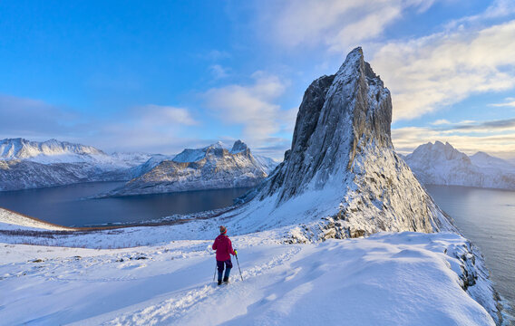 Woman  hiking in winter up to the Segla summit above the village of Fjordgard  at Oeyford on Senja Island in northern Norway