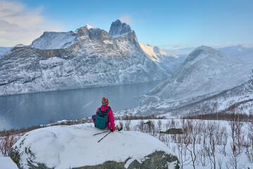 Woman hike in winter up to the Segla summit above the village of Fjordgard  at Oeyford on Senja Island in northern Norway