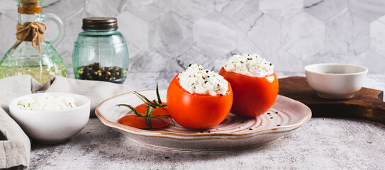 Fresh tomatoes filled with cottage cheese and herbs on a plate on the table web banner