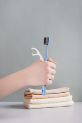 Toothbrush and dental floss in hand against background of toiletries vertical view
