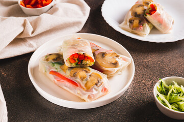 Delicious spring rolls with vegetables and mushrooms in rice paper on a plate on the table