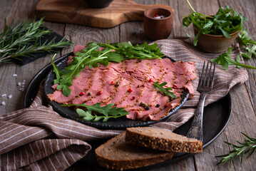 Sliced pastrami meat with rosemary and pepper