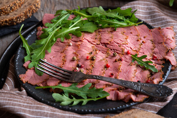 Sliced pastrami meat with rosemary and pepper
