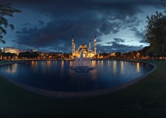 Obraz premium Night view of a mosque with fountain and pond.