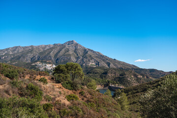 Andalusian landscape with mountain range and reservoir under clear blue sky