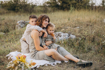 Fototapeta premium Happy Mother with Children Enjoying a Picnic Outdoors in a Meadow Setting