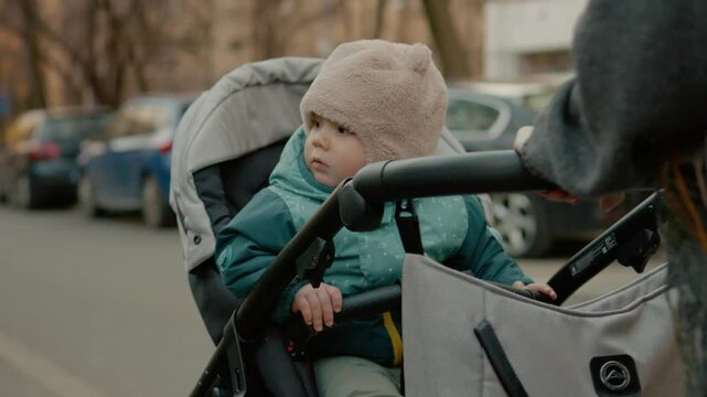 Mother joyfully pushes her small child in a stroller along a smooth pathway. They explore their surroundings while enjoying a delightful stroll together.