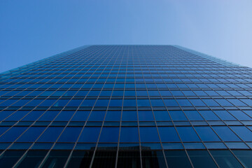 ビルのガラス張りの壁面と快晴の青空