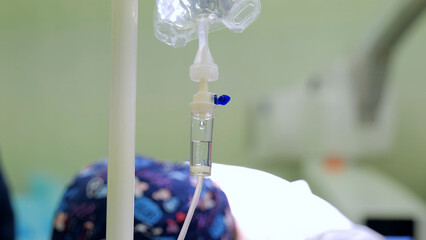 Intravenous fluid slowly dripping from a bag into a chamber as a patient awaits surgery in the...