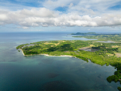 Island with beach and turquoise sea water. Blue sky and clouds. Looc, Tablas Island. Romblon, Philippines.
