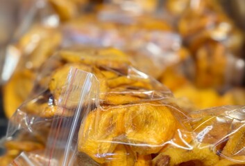 Dried ripe juicy orange persimmons are packed in transparent bags by weight, put up for sale at a supermarket vegetable stand, demonstrates organic, vegetarian and healthy food. Close-up