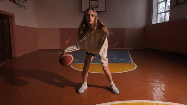 Young female basketball player dribbling in a gym