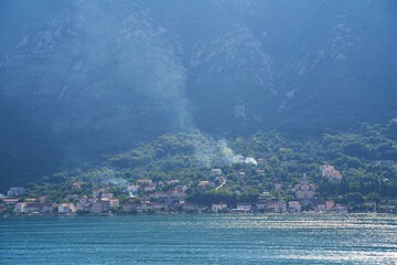 Smoke plume over peaceful mountain village scene.