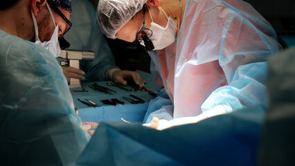 Surgeons in blue scrubs and masks work together in an operating room, using advanced equipment to...