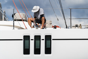 Male Deckhand working on yacht maintenance, servicing winches on a sailboat in shipyard located in Palma de Mallorca in the Balearic islands of Spain