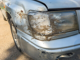 front side of an old damaged silver vehicle headlamp fixed with clear tape
