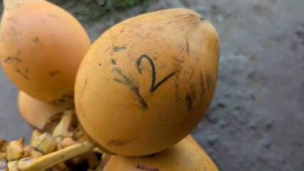 A drinking coconut marked with a number for sale at local fruit and vegetable market stall