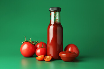 Ketchup in bottle and fresh tomatoes on green background