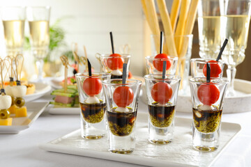 Many different tasty canapes and wine on white table