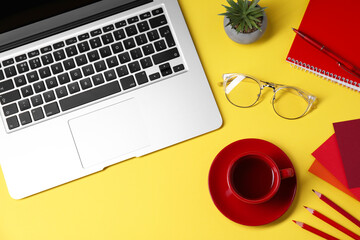 Designer's workplace. Flat lay composition with stationery, laptop and cup of coffee on yellow...