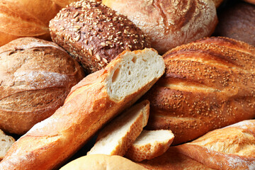 Whole and cut loafs of bread on table, closeup
