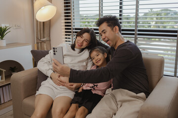 Obraz premium lovely family spend time together in their house, a pregnant mother sits on the couch with her husband and daughter enjoying a happy time together on a weekend