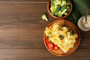 Tasty pasta casserole with cheese and broccoli served on wooden table, flat lay. Space for text
