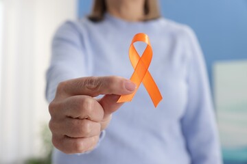 Multiple Sclerosis awareness. Woman with orange ribbon at home, closeup