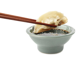 Dipping tasty gyoza (dumpling) into soy sauce on white background
