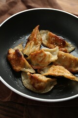 Tasty fried gyoza (dumplings) on wooden table, closeup