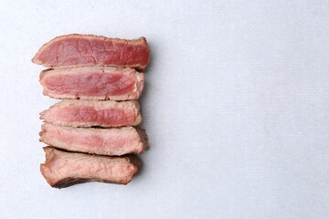 Delicious sliced beef tenderloin with different degrees of doneness on light table, top view. Space...