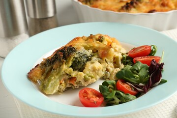 Tasty vegetable casserole and salad on white wooden table, closeup