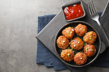 Tasty meatballs in baking dish served on grey table, flat lay. Space for text
