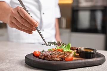 Professional chef serving dish at table indoors, closeup
