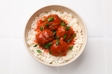 Tasty meatballs with sauce and rice on white tiled table, top view