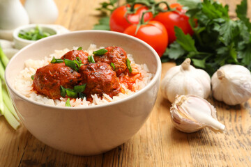 Tasty meatballs with sauce, rice and products on wooden table, closeup