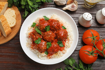 Tasty meatballs with sauce, rice and products on wooden table, flat lay