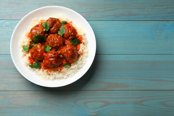 Tasty meatballs with sauce and rice on light blue wooden table, top view. Space for text