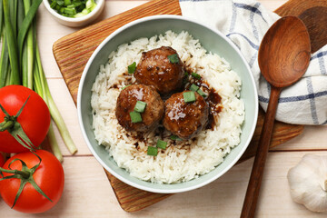 Delicious rice with meatballs, sauce and green onions on white wooden table, flat lay